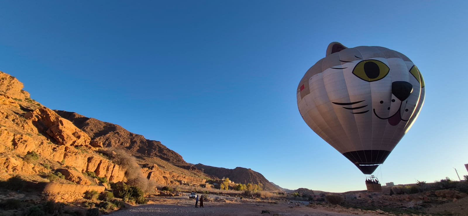 Hot air balloon drifting through a southern Moroccan valley at dawn