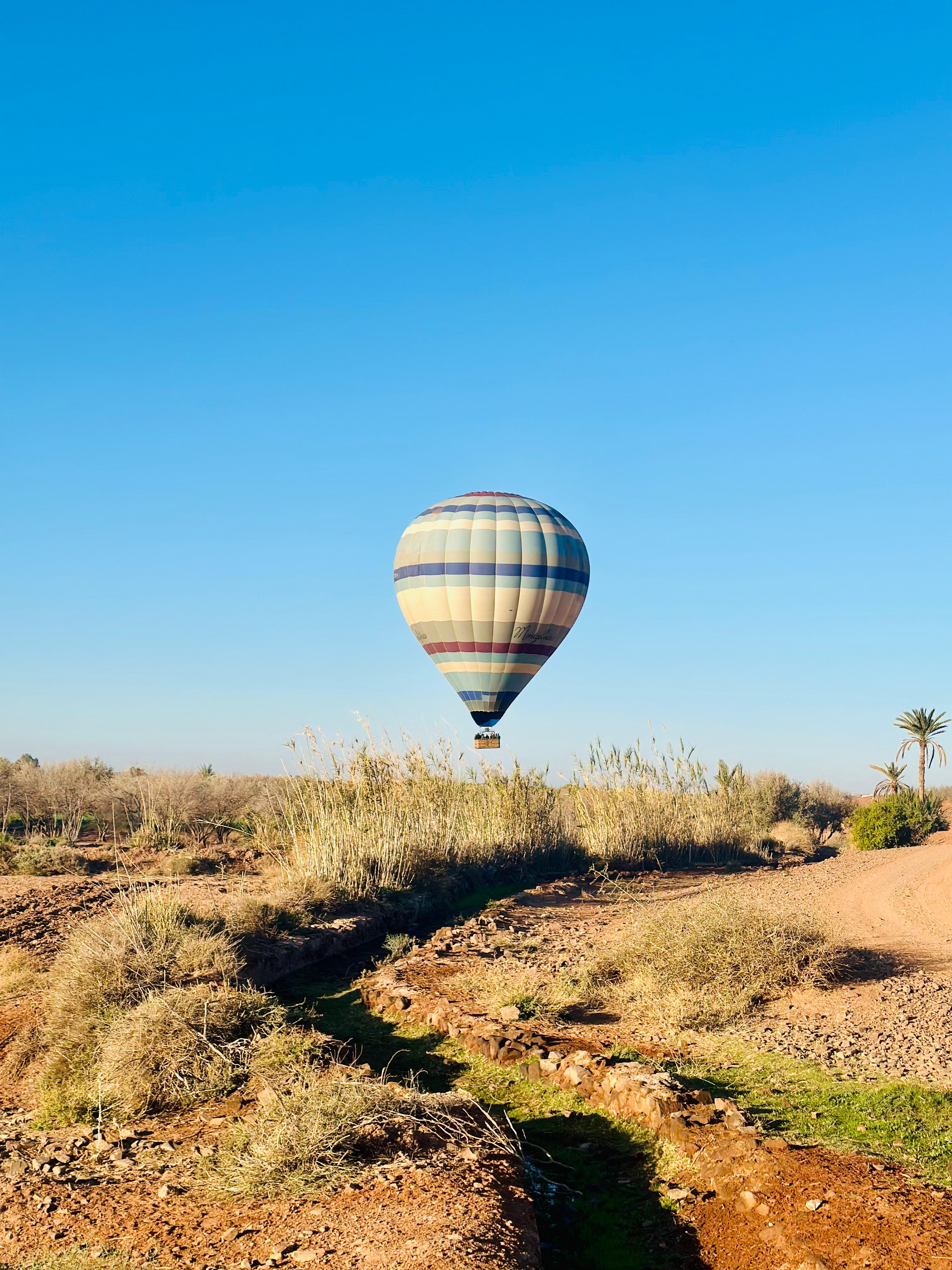 Hot air balloon rising over Ouarzazate desert terrain