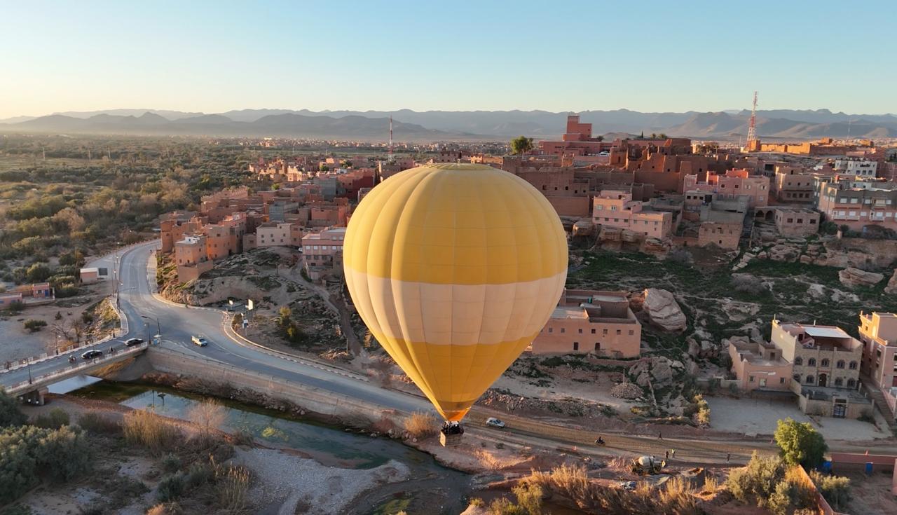 Golden hot air balloon floating beside Tinghir town at sunrise